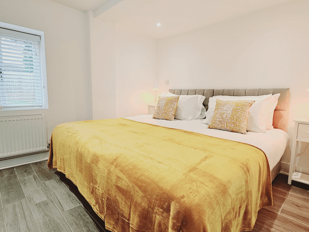 Super king bedroom with yellow bedding in Grade 2 listed Oak Suite apartment, Farnham town centre Super king bedroom with yellow bedding in Grade 2 listed Oak Suite apartment, Farnham town centre