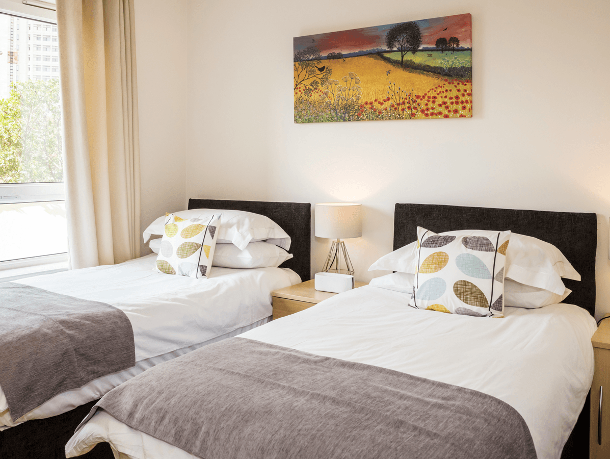 Bright twin bedroom with contemporary bedding and window view at The Amber Suite, Centrium, Woking Bright twin bedroom with contemporary bedding and window view at The Amber Suite, Centrium, Woking