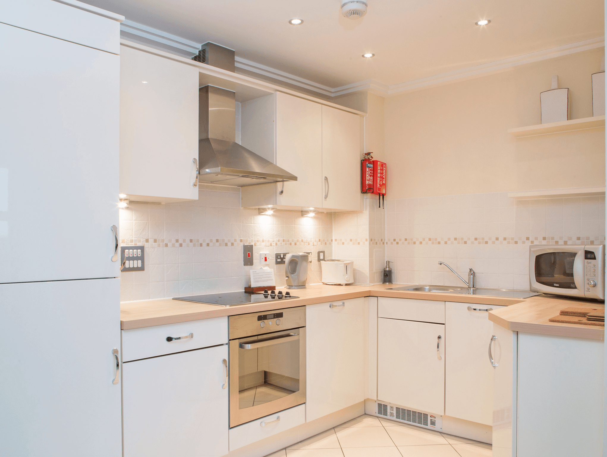 Modern kitchen with white cabinetry, integrated oven, and under-cabinet lighting at The Elm Suite, Kings Road, Reading Modern kitchen with white cabinetry, integrated oven, and under-cabinet lighting at The Elm Suite, Kings Road, Reading