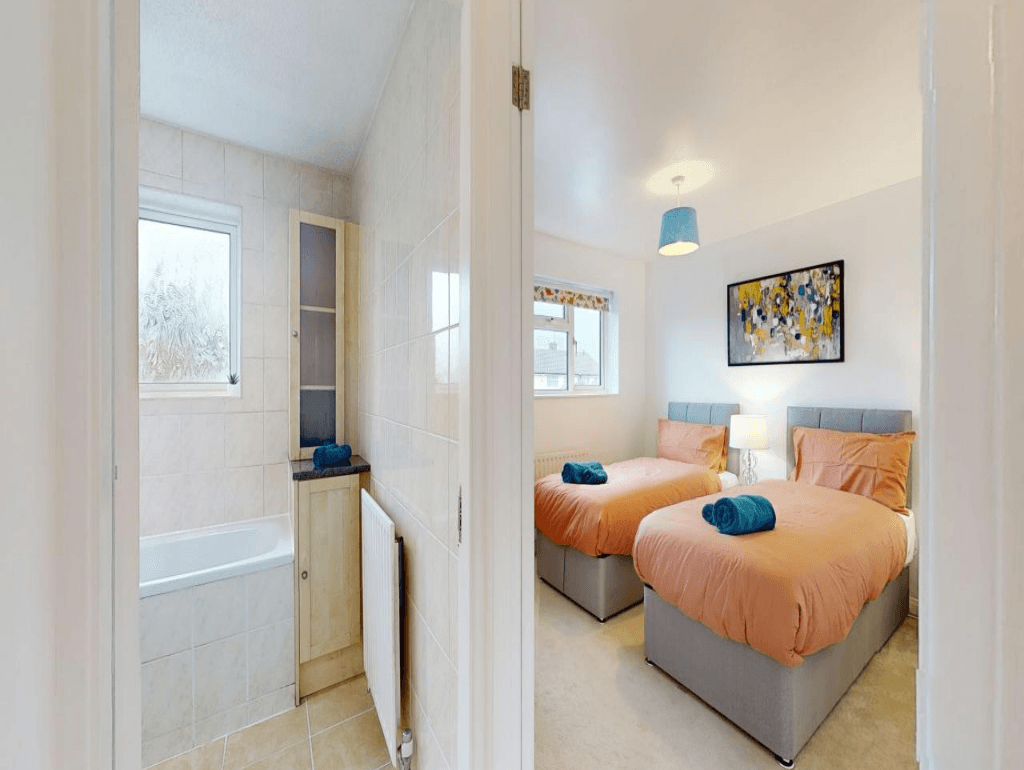 Twin bedroom with matching peach bedding, blue cushions, mirrored wardrobe, and window view – Parlaunt House - Slough Twin bedroom with matching peach bedding, blue cushions, mirrored wardrobe, and window view – Parlaunt House - Slough