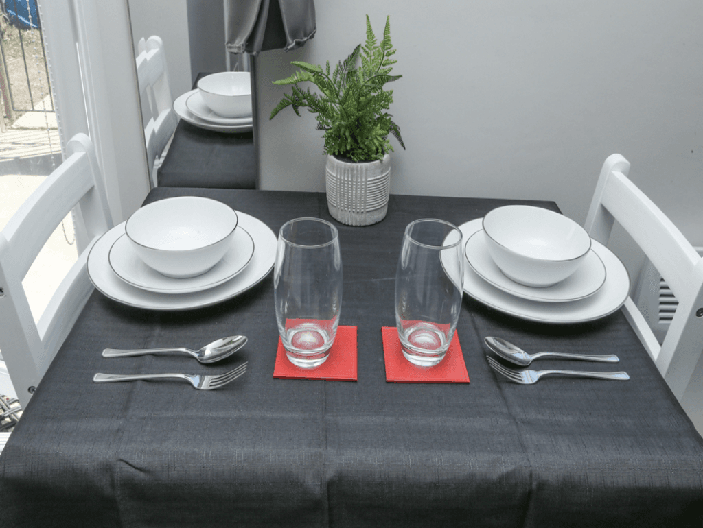 Dining table set for two, white dishes, coffee cups, and view of studio windows – Crofton Park, London Dining table set for two, white dishes, coffee cups, and view of studio windows – Crofton Park, London