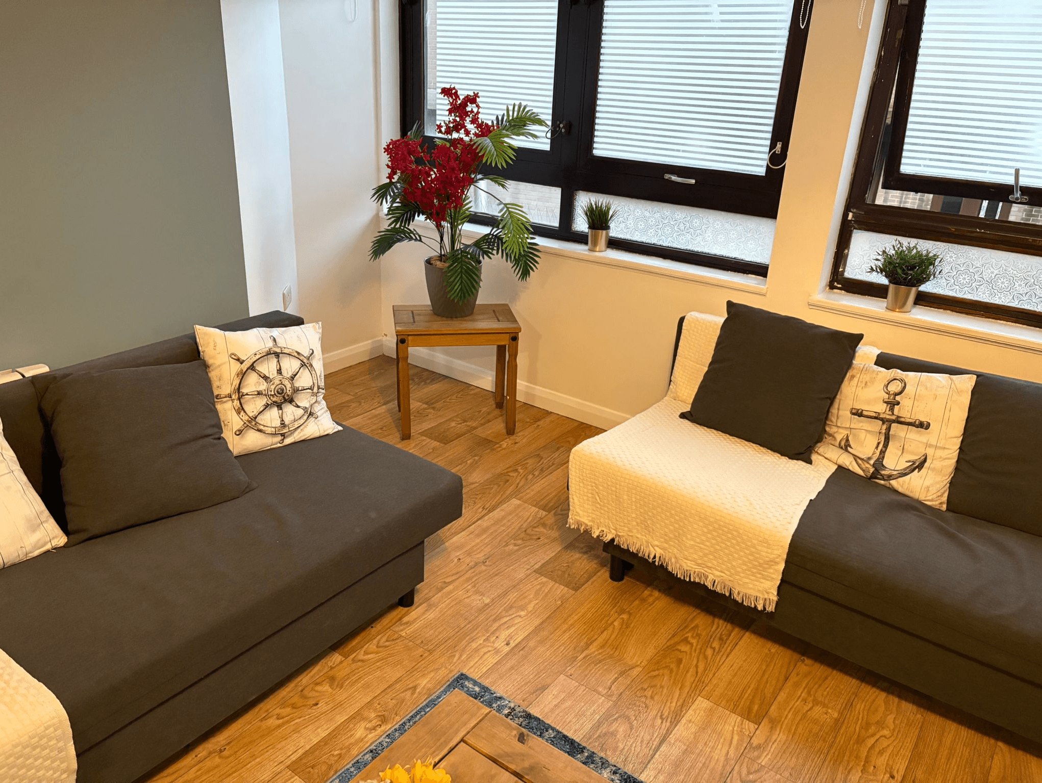 Bright living room with two grey sofas, coffee table, and floral centerpiece by large windows Bright living room with two grey sofas, coffee table, and floral centerpiece by large windows