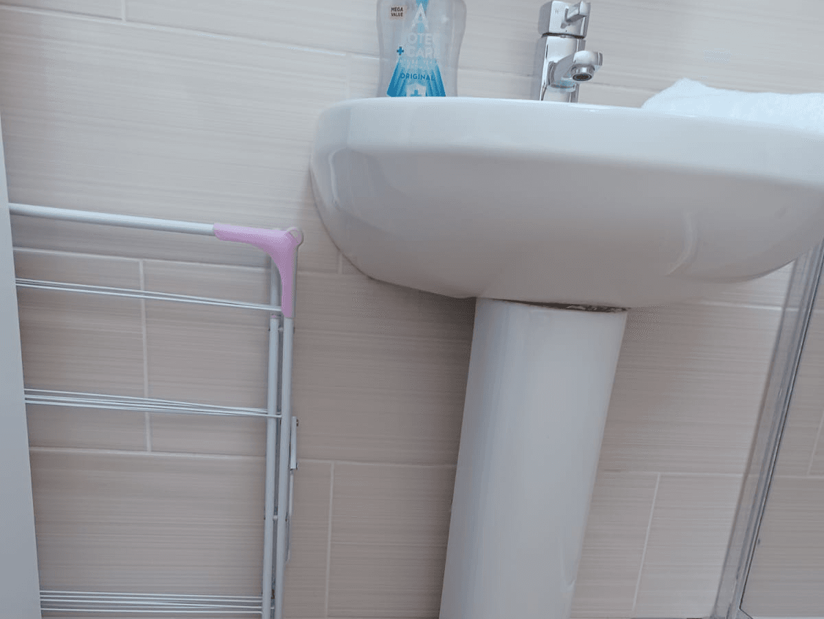 White pedestal sink and towel rail in bright bathroom White pedestal sink and towel rail in bright bathroom