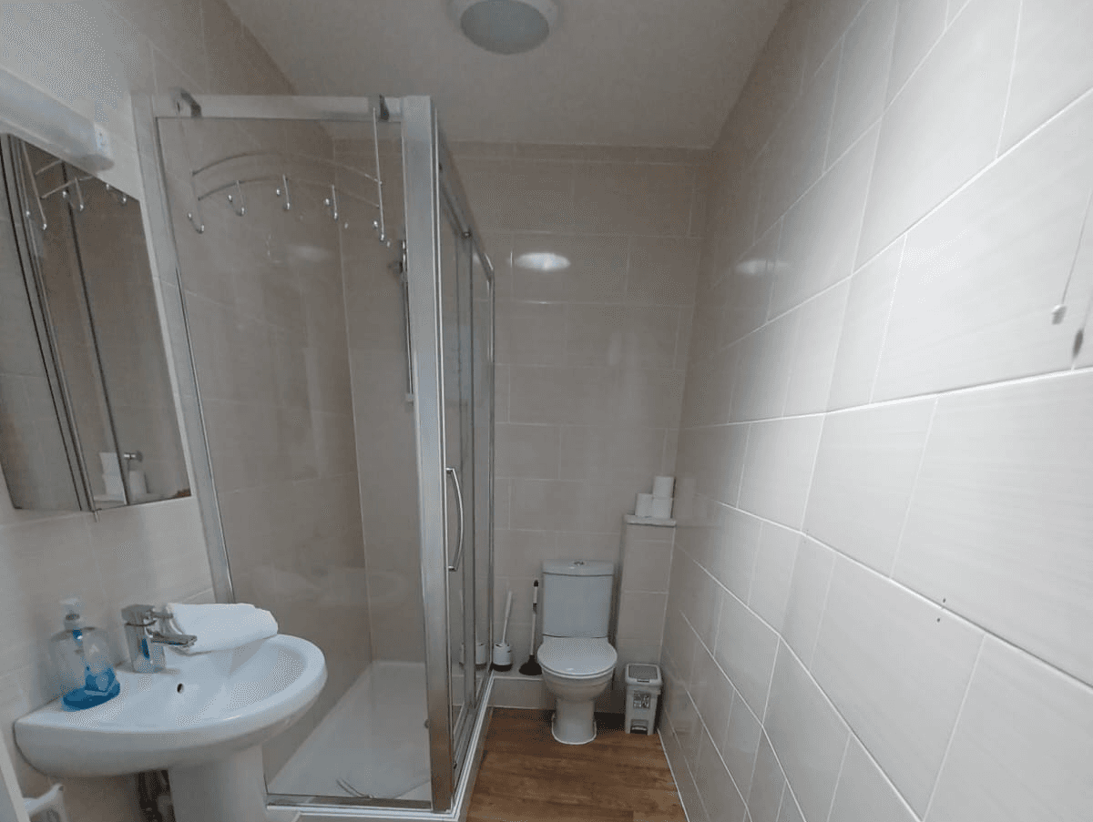 Modern bathroom with glass shower enclosure, basin, toilet, and neutral tiles – Castle 16 - Southampton Modern bathroom with glass shower enclosure, basin, toilet, and neutral tiles – Castle 16 - Southampton