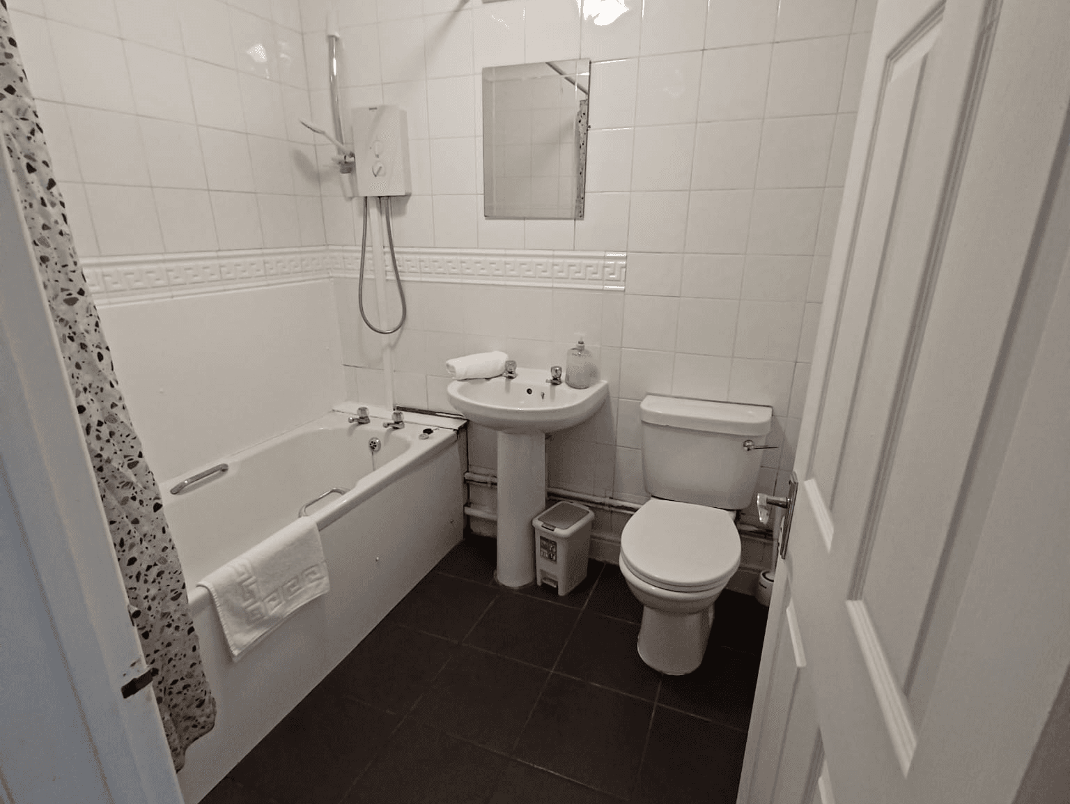 Modern bathroom with white tiling, full-size bath, shower, basin, and towels – Wilton H1 - Southampton Modern bathroom with white tiling, full-size bath, shower, basin, and towels – Wilton H1 - Southampton