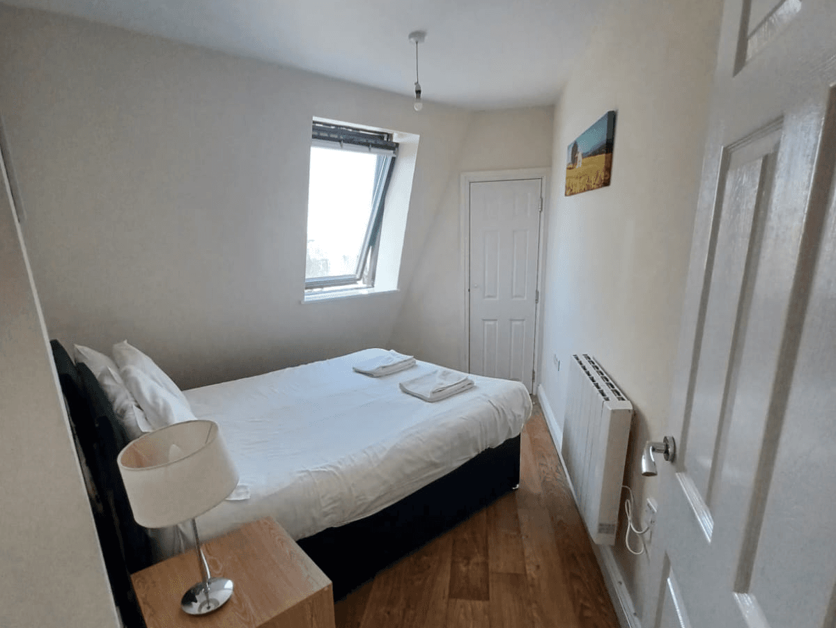 Double bedroom with light wood floors, bedside lamp, and large window – Castle 16 - Southampto Double bedroom with light wood floors, bedside lamp, and large window – Castle 16 - Southampto
