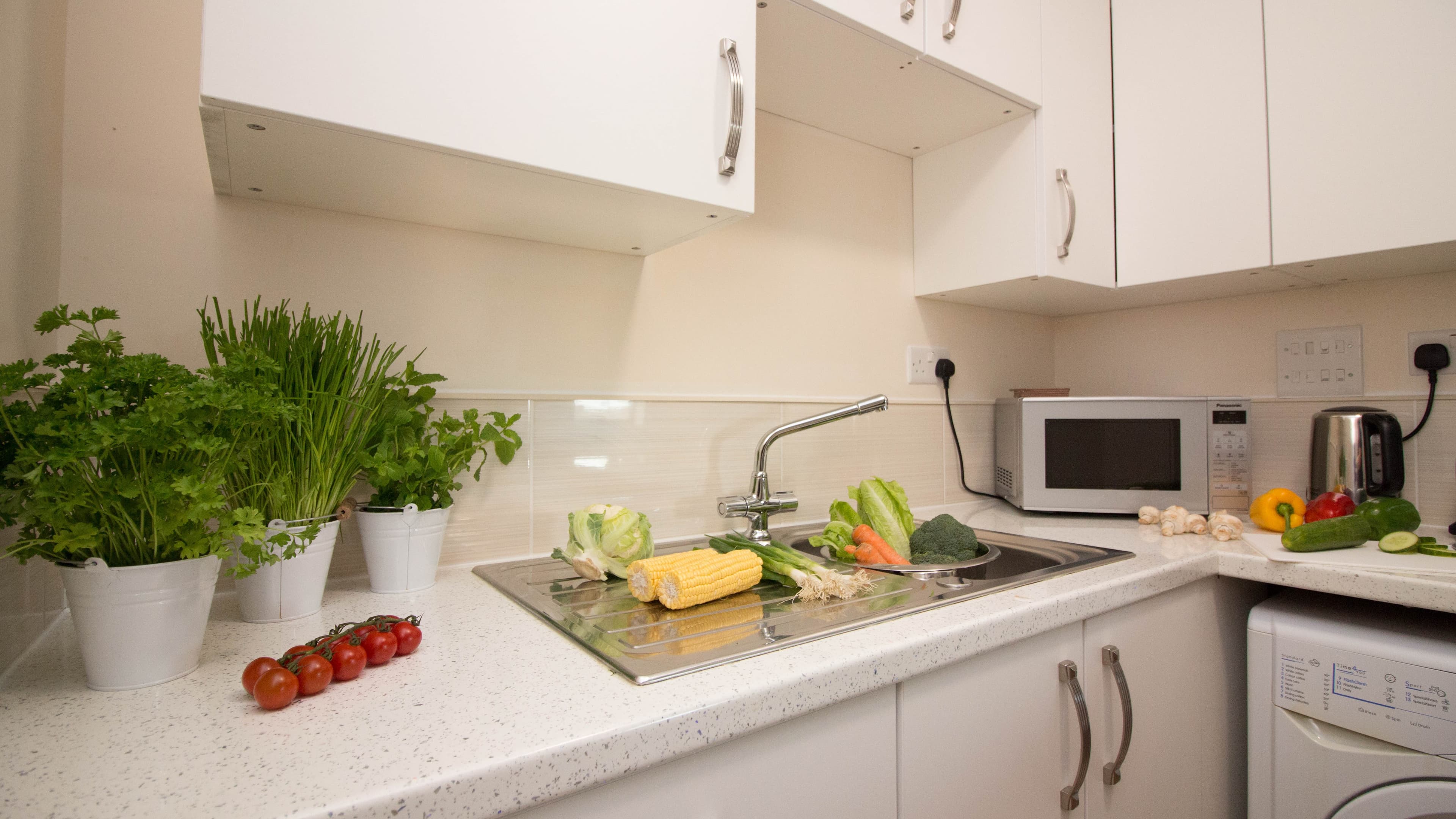 Modern white kitchen with fresh herbs, cutting board, and fully equipped appliances – Castle 17 - Southampton Modern white kitchen with fresh herbs, cutting board, and fully equipped appliances – Castle 17 - Southampton
