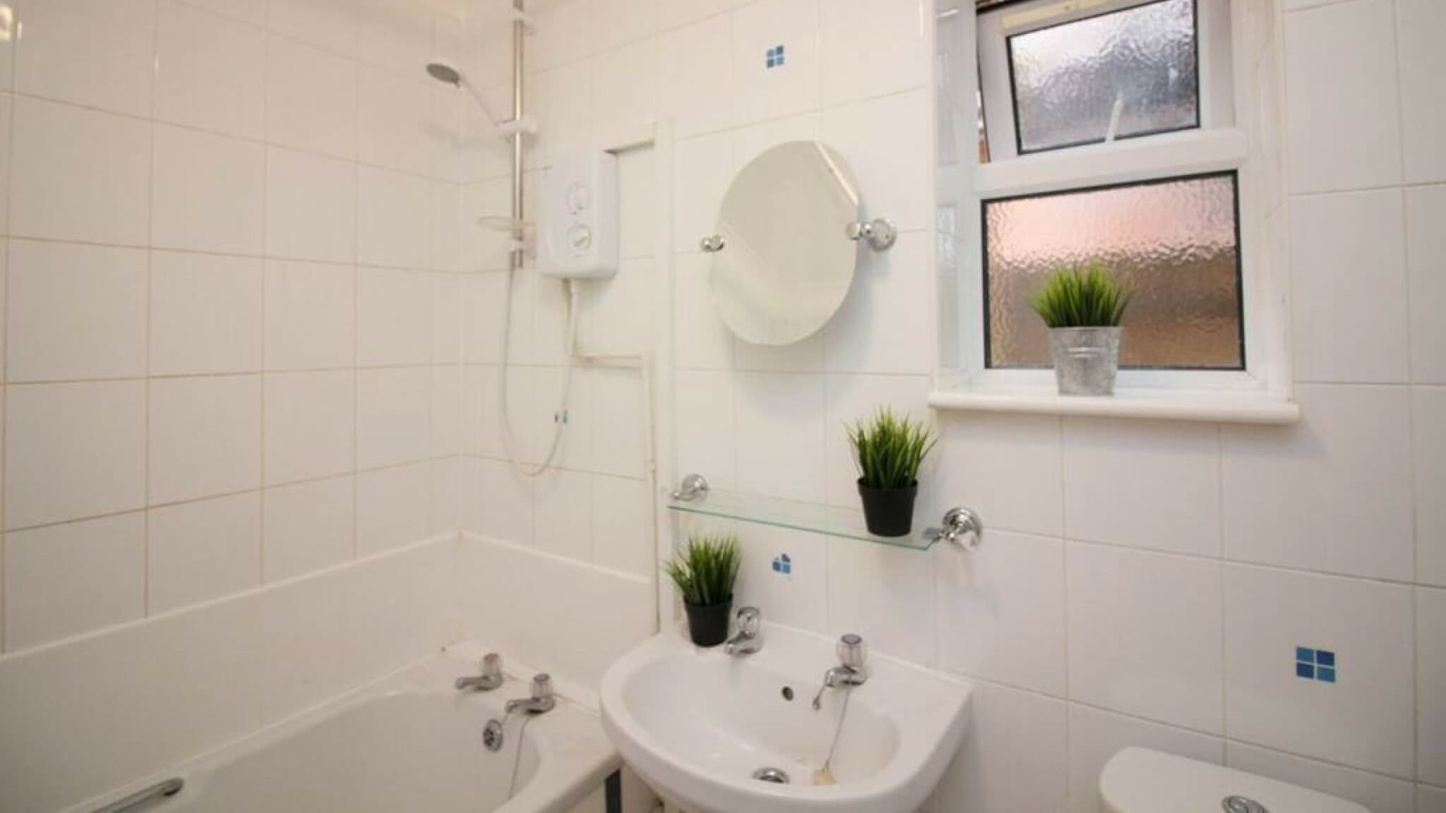 Bright bathroom with white wall tiles, full-size bathtub, overhead shower, modern sink and accessories – Wilton H2 - Southampton Bright bathroom with white wall tiles, full-size bathtub, overhead shower, modern sink and accessories – Wilton H2 - Southampton