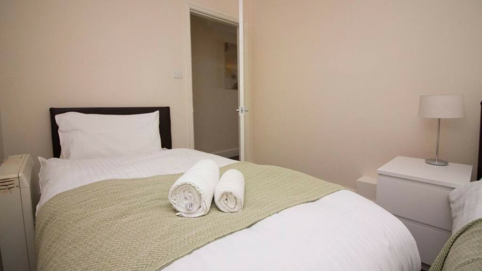 Double bed with crisp white cotton linens, green velvet accent cushion, and bedside lamp – Wilton H2 - Southampton Double bed with crisp white cotton linens, green velvet accent cushion, and bedside lamp – Wilton H2 - Southampton