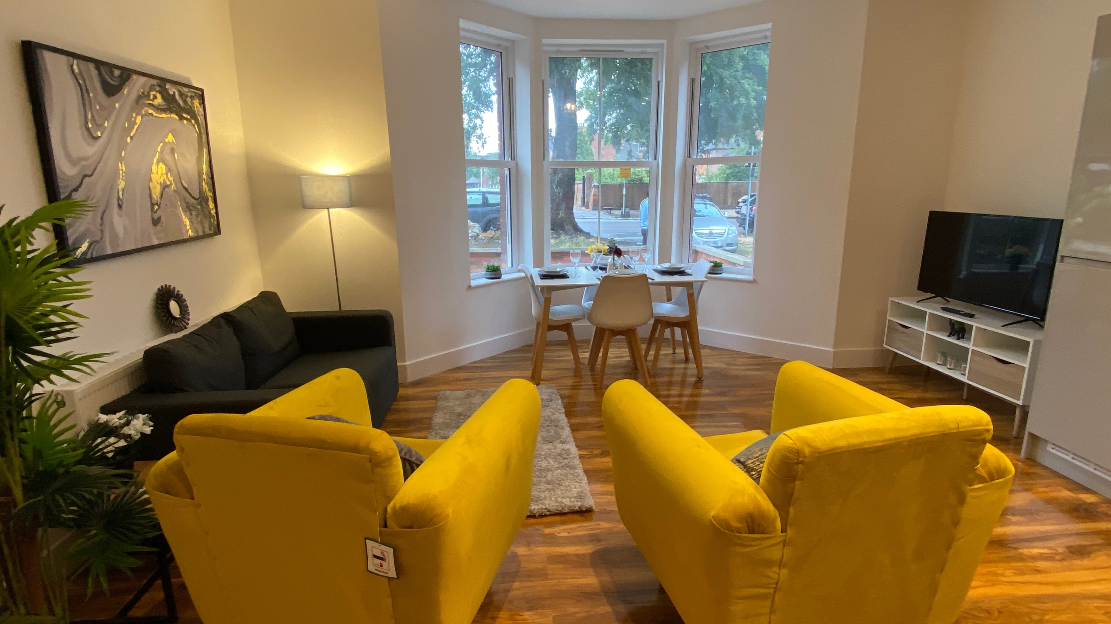 Bright living area with double bed, sofa, bold accent pillows, and flat-screen TV – De Parys Flat 1, Bedford Bright living area with double bed, sofa, bold accent pillows, and flat-screen TV – De Parys Flat 1, Bedford