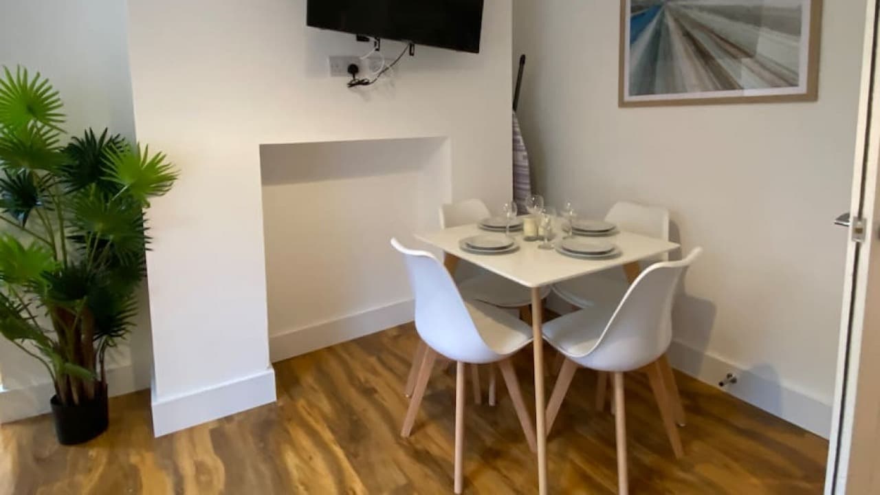 Dining table set for two with white plates and cups in bright alcove living space – De Parys Flat 2, Bedford Dining table set for two with white plates and cups in bright alcove living space – De Parys Flat 2, Bedford