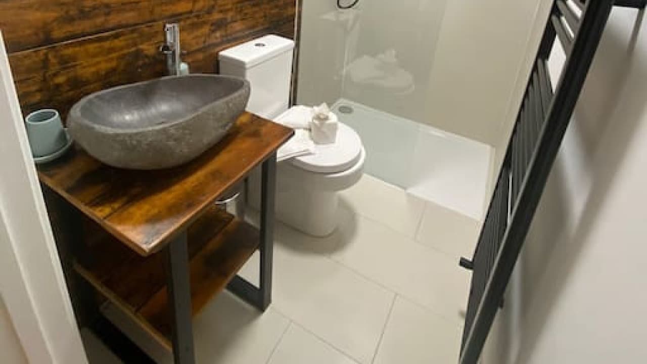 Stylish ensuite bathroom with round stone basin, modern tap, glass walk-in shower, and towel rail – De Parys Flat 3, Bedford Stylish ensuite bathroom with round stone basin, modern tap, glass walk-in shower, and towel rail – De Parys Flat 3, Bedford