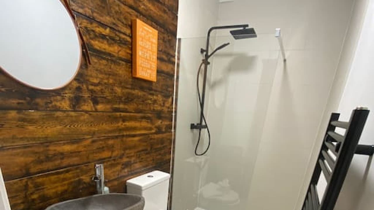 Contemporary bathroom featuring wooden wall, round mirror, and glass walk-in shower enclosure – De Parys Flat 3, Bedford Contemporary bathroom featuring wooden wall, round mirror, and glass walk-in shower enclosure – De Parys Flat 3, Bedford