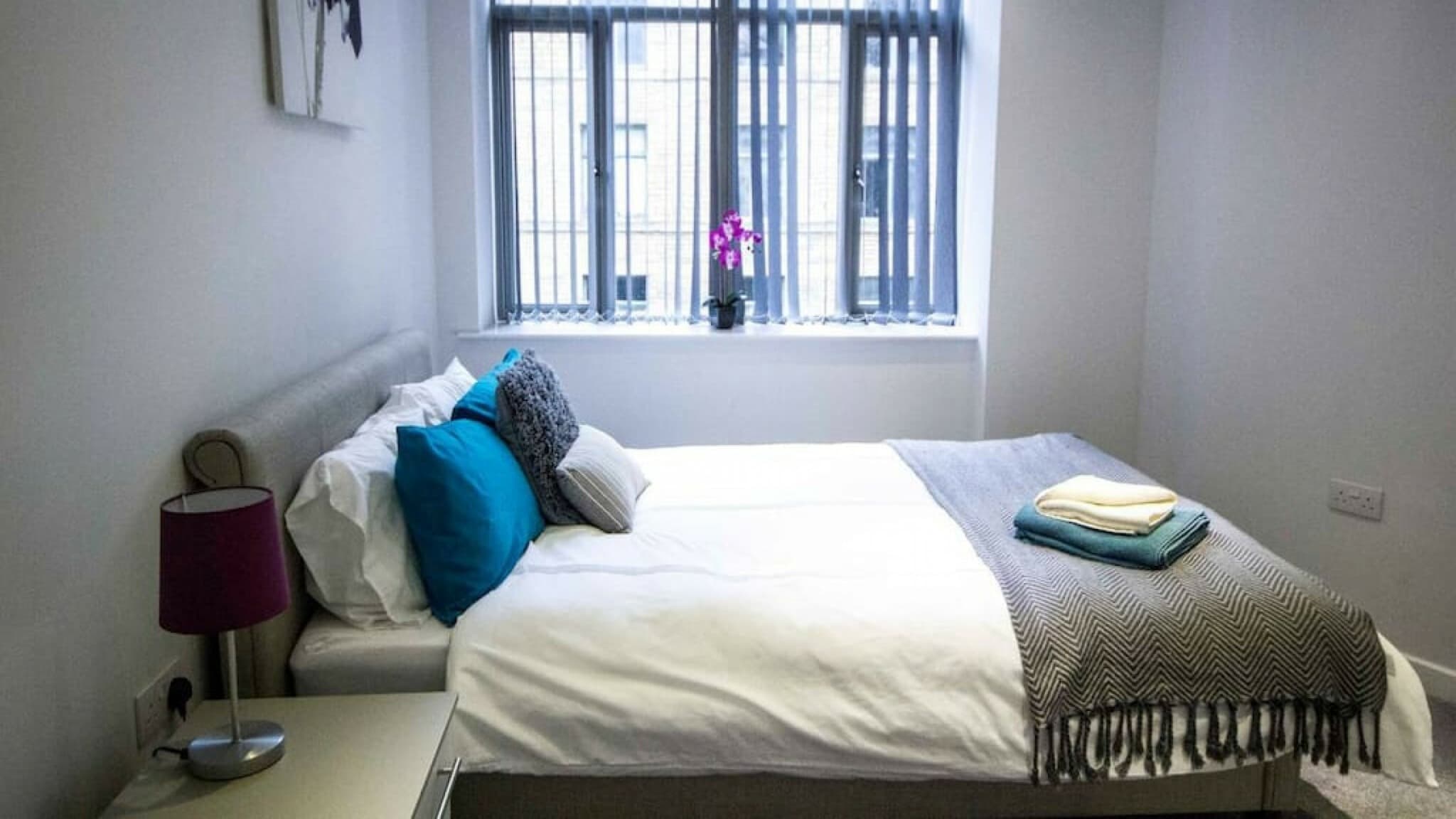 Double bedroom with teal throw, white linens, bedside lamp and window bench – Grattan 2 - Bradford Double bedroom with teal throw, white linens, bedside lamp and window bench – Grattan 2 - Bradford