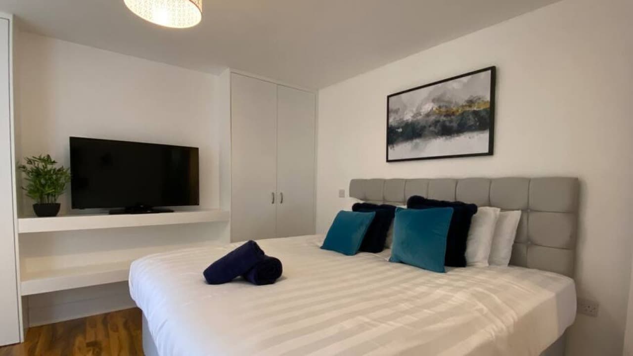 Double bedroom with grey and teal bedding, wall art, built-in wardrobe, and TV unit – Westminster - Bradford Double bedroom with grey and teal bedding, wall art, built-in wardrobe, and TV unit – Westminster - Bradford