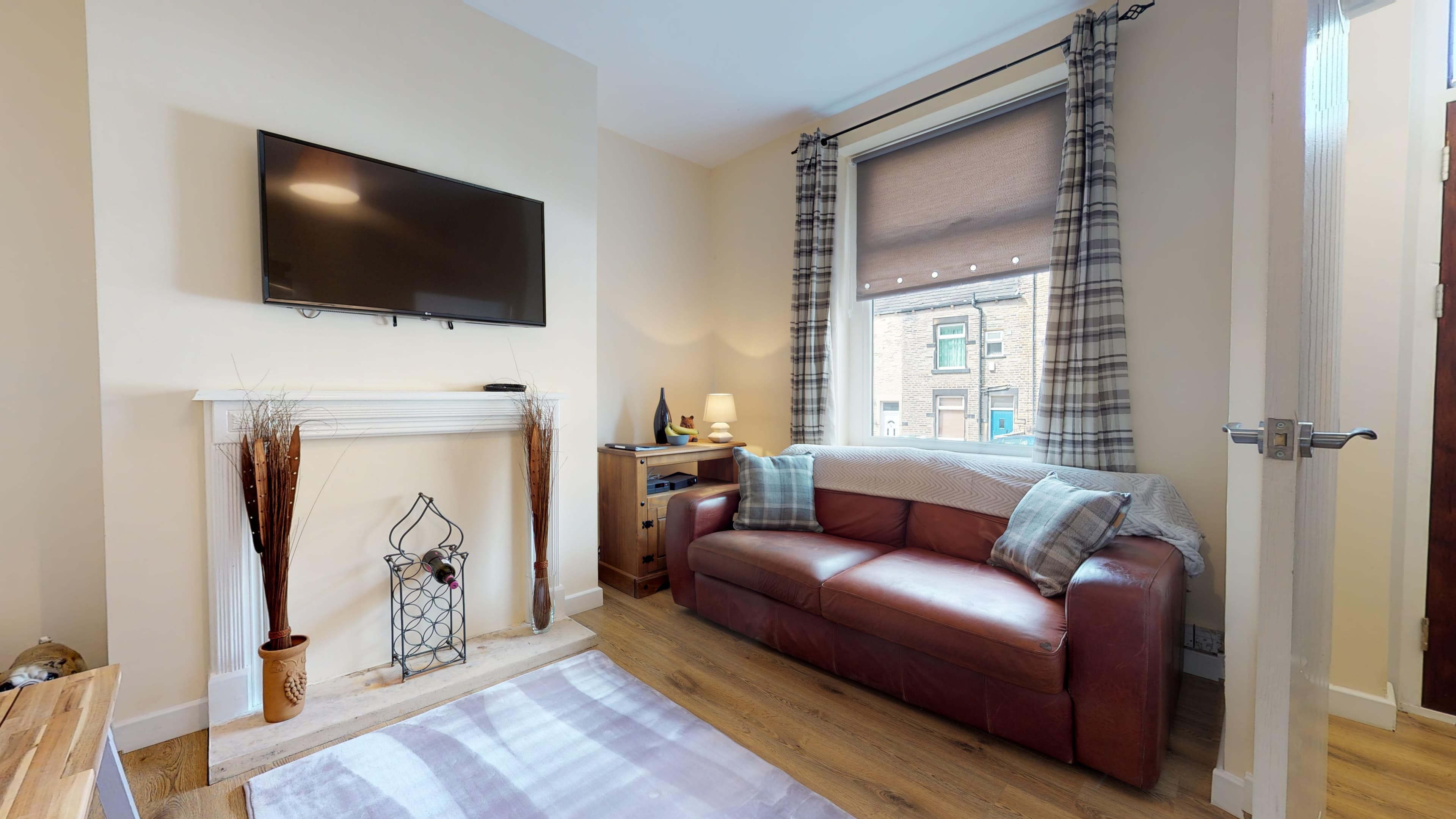 Living room with fireplace, brown leather sofas, striped rug, and wall-mounted TV – Westminster - Bradford Living room with fireplace, brown leather sofas, striped rug, and wall-mounted TV – Westminster - Bradford