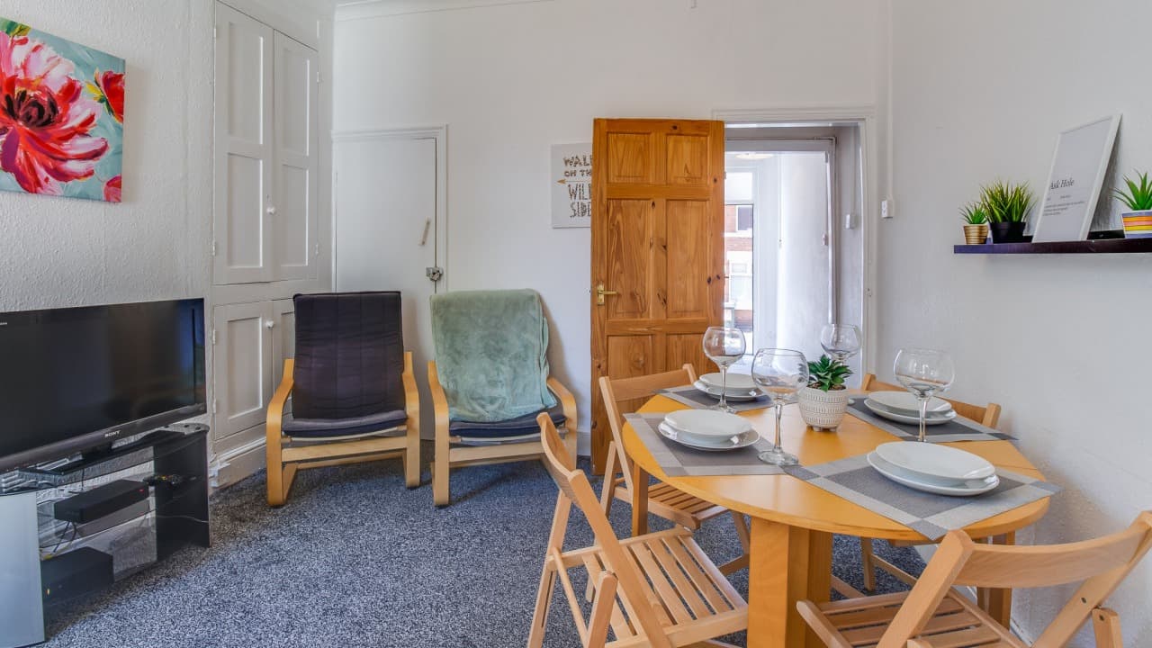 Cozy lounge with TV, dining table for four, two wood chairs, and bright window – Terry Road, Coventry Cozy lounge with TV, dining table for four, two wood chairs, and bright window – Terry Road, Coventry