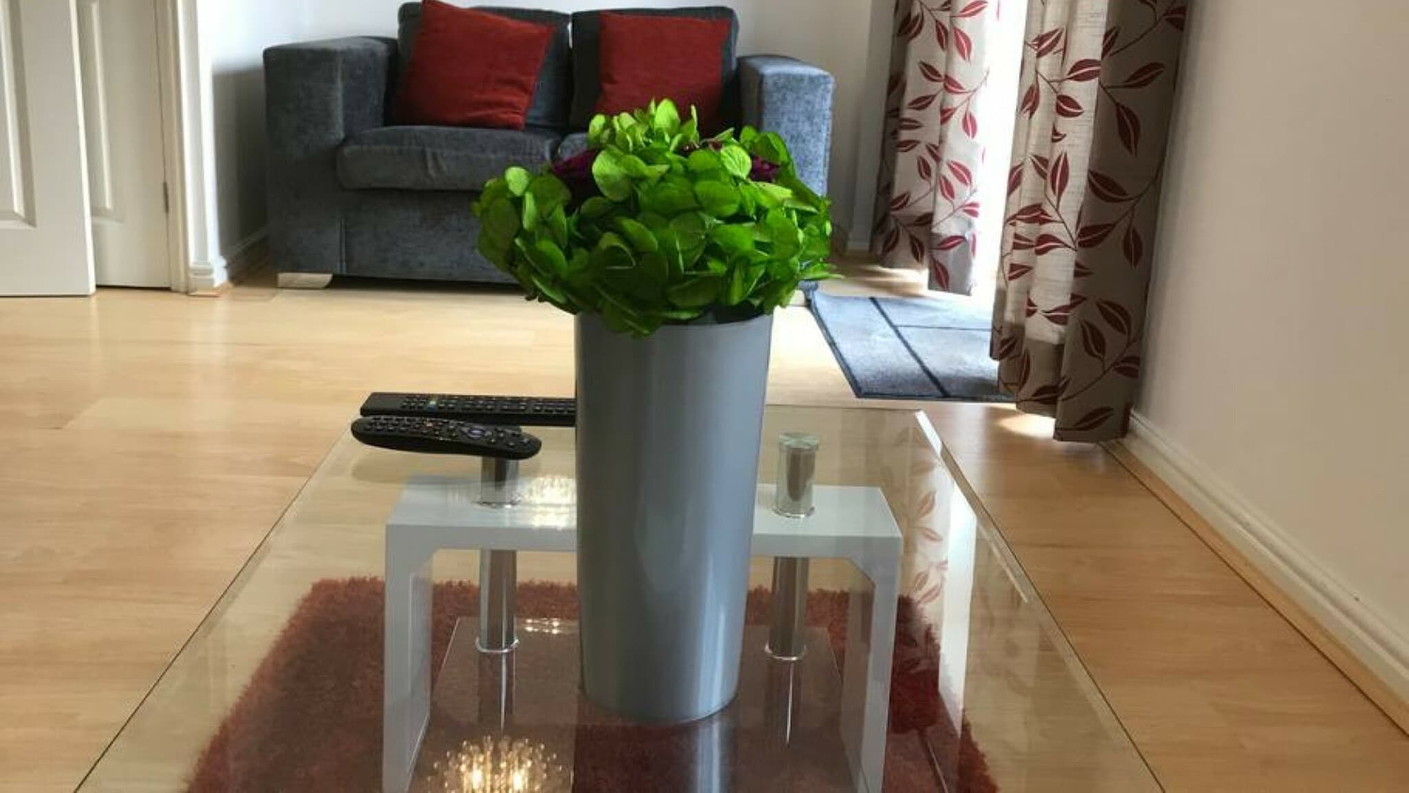 Modern living room with glass coffee table, flower centerpiece, and tiled floor at Cole Green Lane-Herts, Welwyn Garden City Modern living room with glass coffee table, flower centerpiece, and tiled floor at Cole Green Lane-Herts, Welwyn Garden City